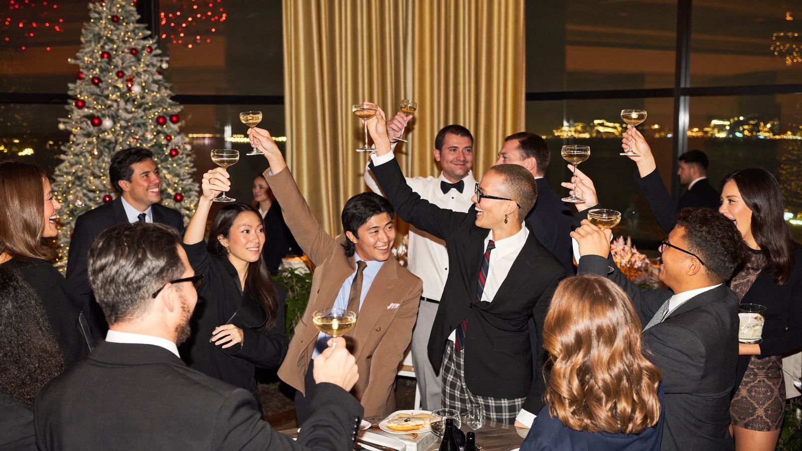 Company holiday party in San Diego Company year-end party with guests raising glasses beside a decorated holiday tree